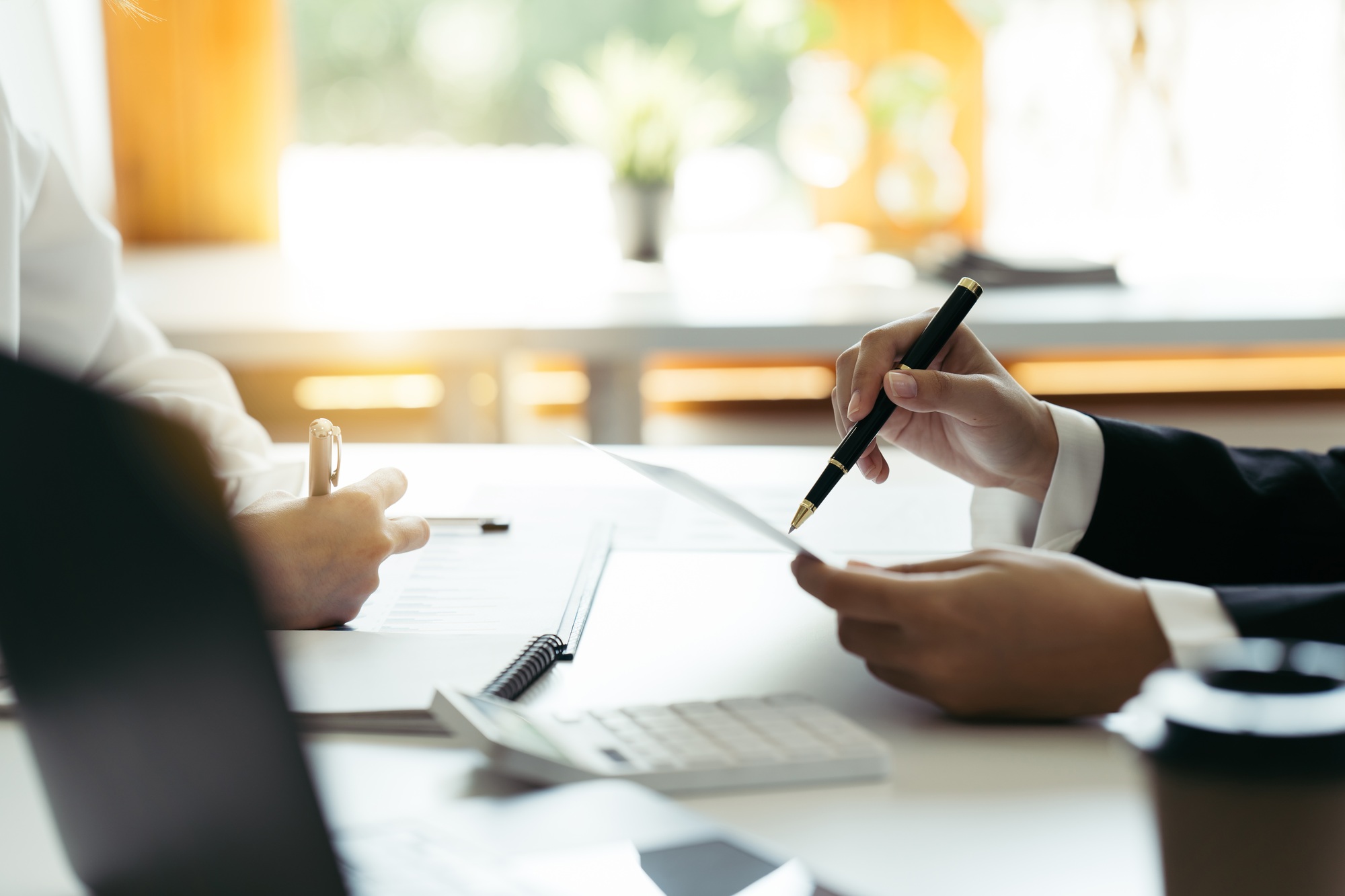 Financial adviser working with client, calculating and analyzing data at the table in office.